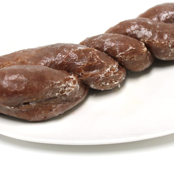 A chocolate glazed twist donut with white sugar crystals on a white rectangular plate.