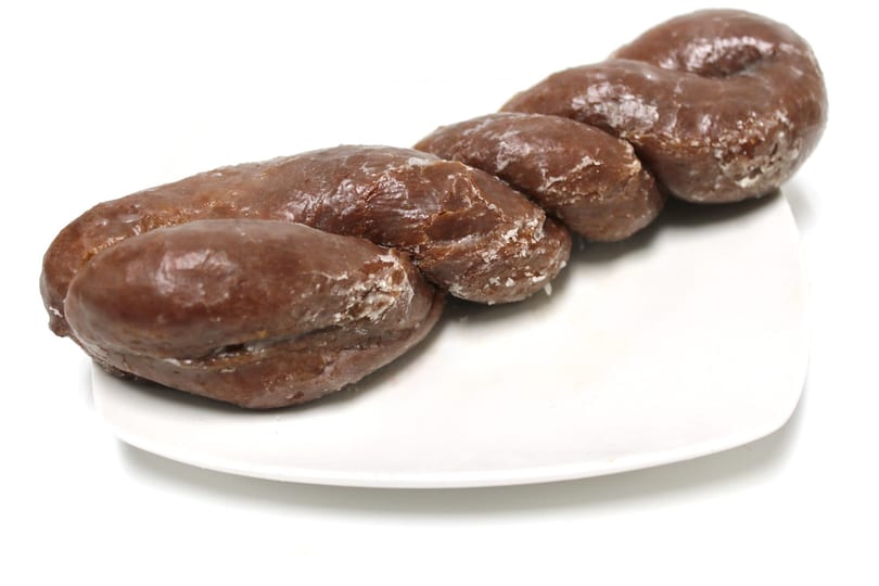 A chocolate glazed twist donut with white sugar crystals on a white rectangular plate.