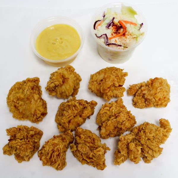 Crispy fried chicken pieces with a side of coleslaw and a cup of honey mustard sauce.