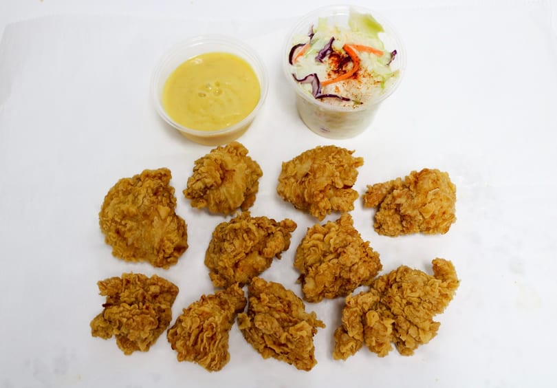 Crispy fried chicken pieces with a side of coleslaw and a cup of honey mustard sauce.