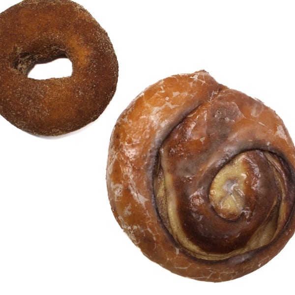 A cinnamon sugar donut and a glazed cinnamon roll on a white background.