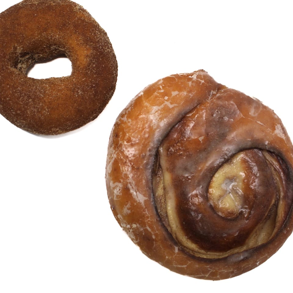 A cinnamon sugar donut and a glazed cinnamon roll on a white background.