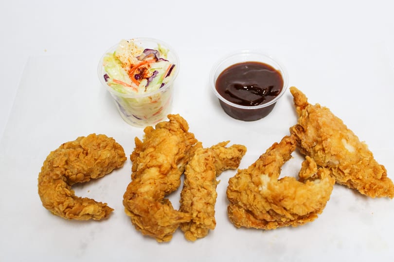 Crispy fried chicken pieces with a side of coleslaw and barbecue dipping sauce.