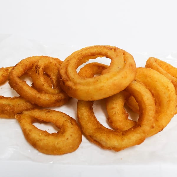 A pile of golden-brown, crispy onion rings on a white background.