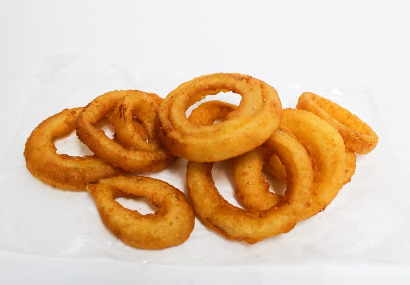 A pile of golden-brown, crispy onion rings on a white background.